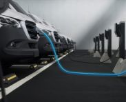 Fleet of generic electric EV delivery vans charging on charging stations