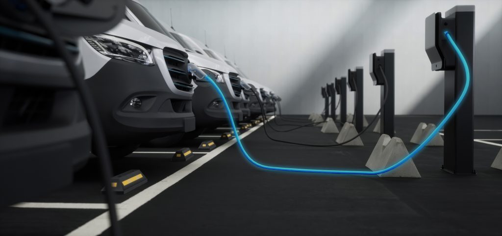 Fleet of generic electric EV delivery vans charging on charging stations