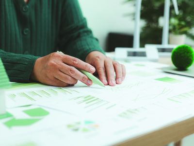Eco-friendly,Business,Concept,With,Hand,Analyzing,Financial,Charts,And,Green